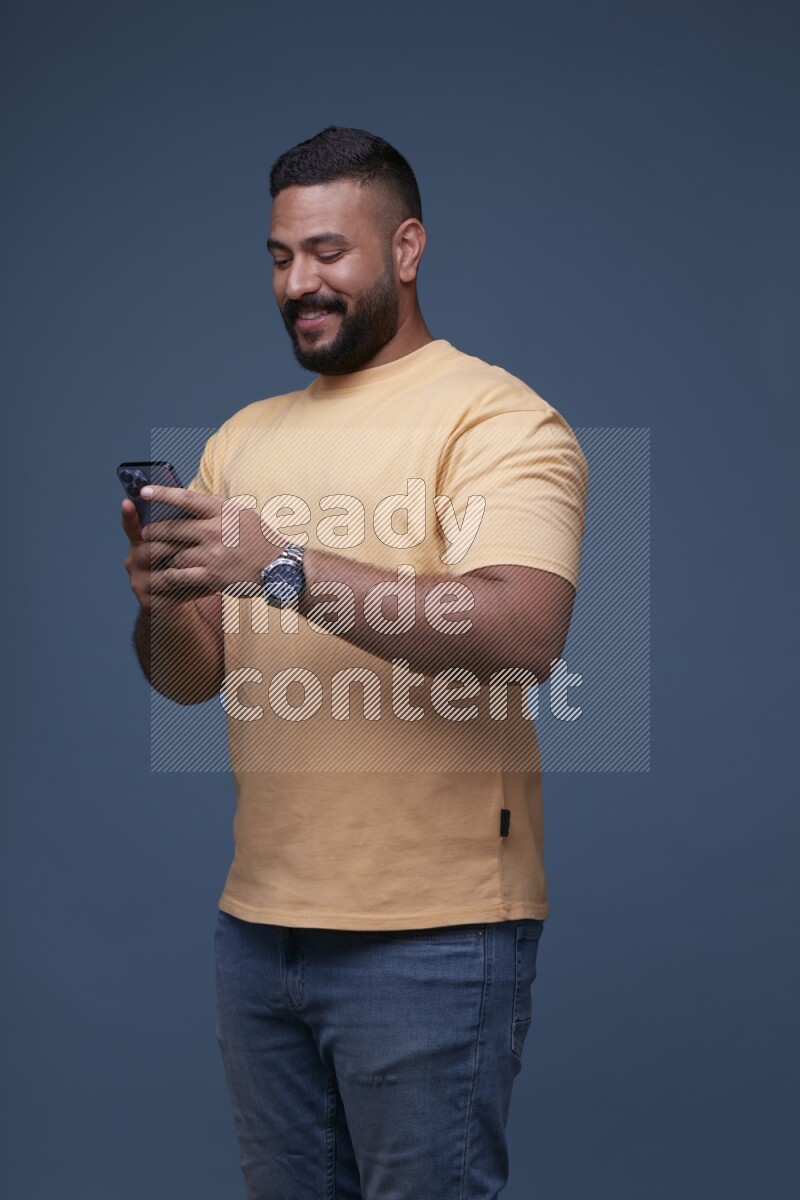 A man Texting on his phone on Blue Background wearing Orange T-shirt
