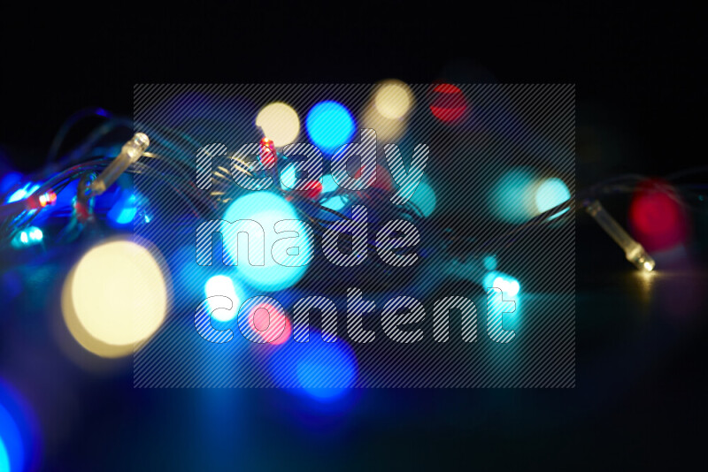 Light bulbs glowing against backdrop of multicolord bokeh