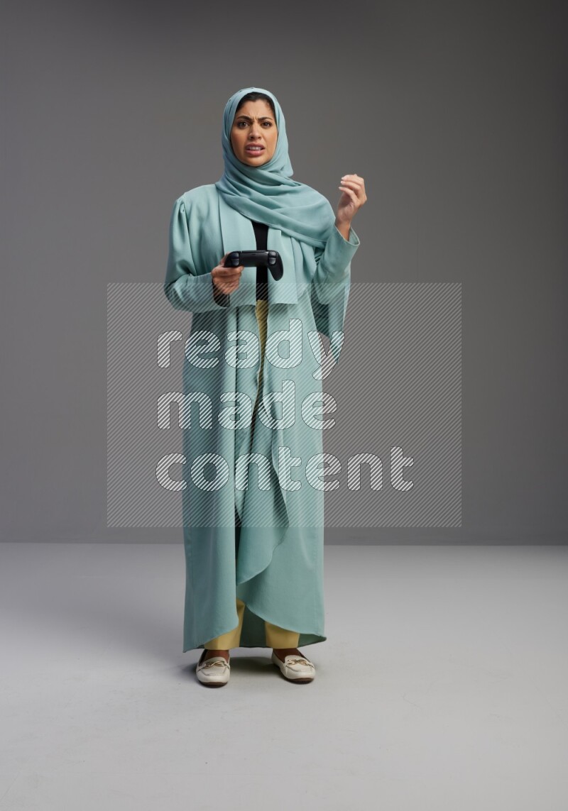 Saudi Woman wearing Abaya standing Playing Games on Gray background