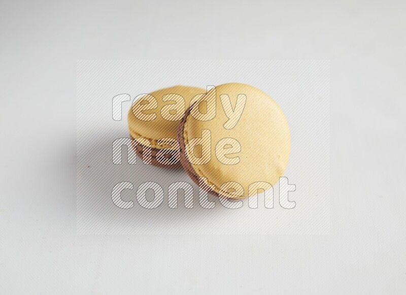 45º Shot of two Yellow and Brown Chai Latte macarons on white background