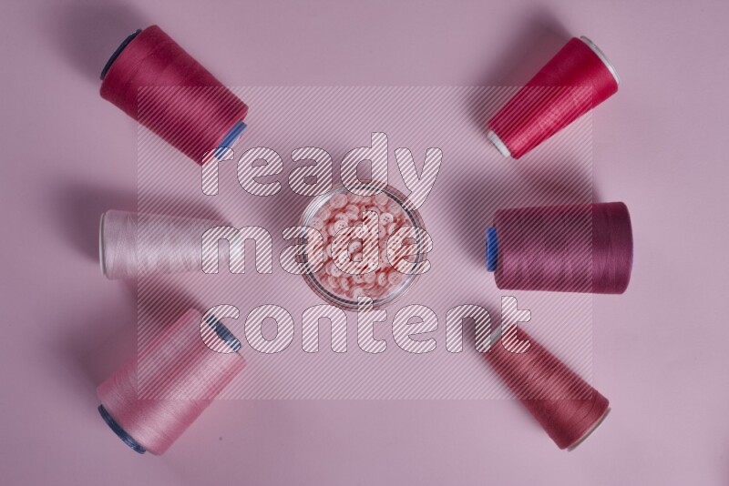 A pink collection of sewing and tailoring tools arranged on a pink background