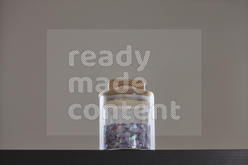 Sequins in a glass jar on black background