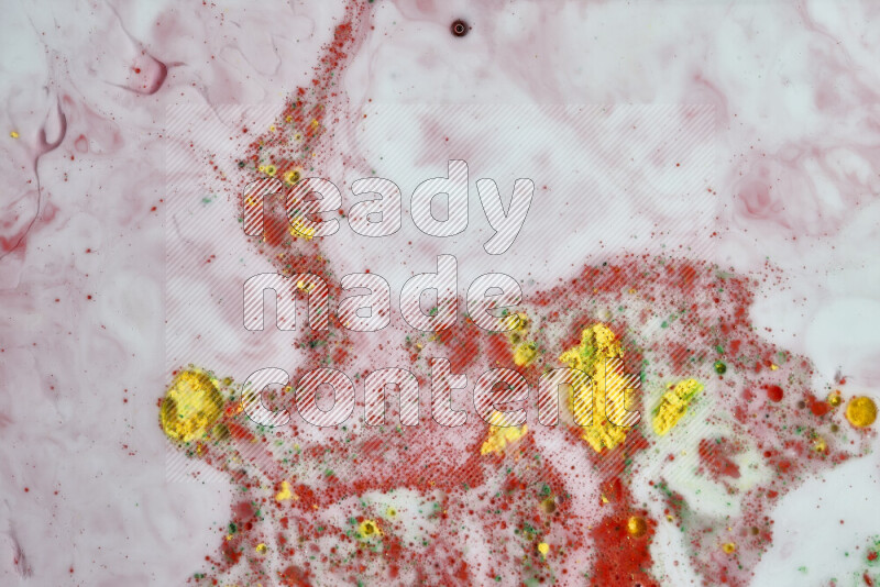 The image captures a splatter of yellow, red and green paint over a white backdrop