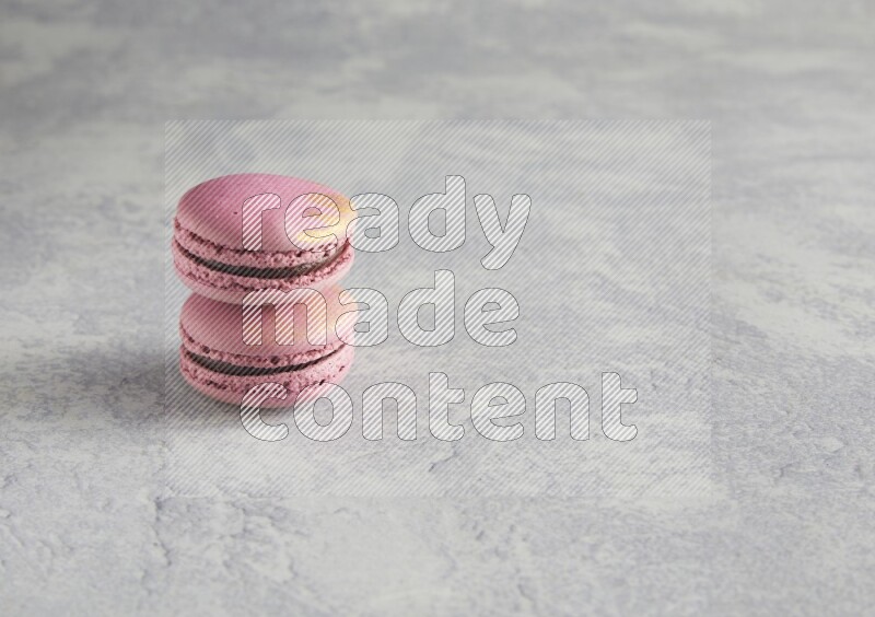 45º Shot of two Purple Strawberry macarons on white  marble background