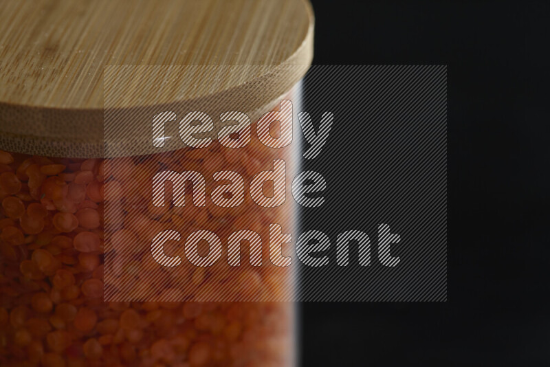 Lentils in a glass jar on black background