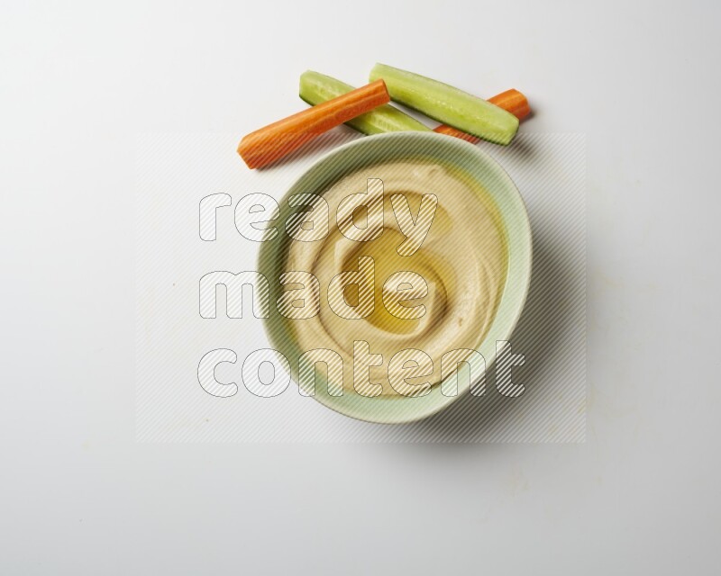 Hummus in a green plate garnished with olive oil on a white background