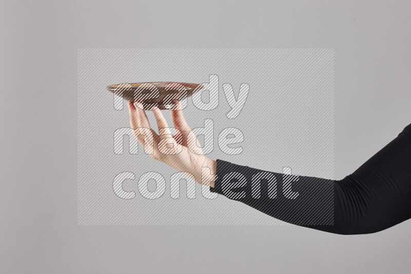 A woman in black abaya holding different pottery essentials in different positions
