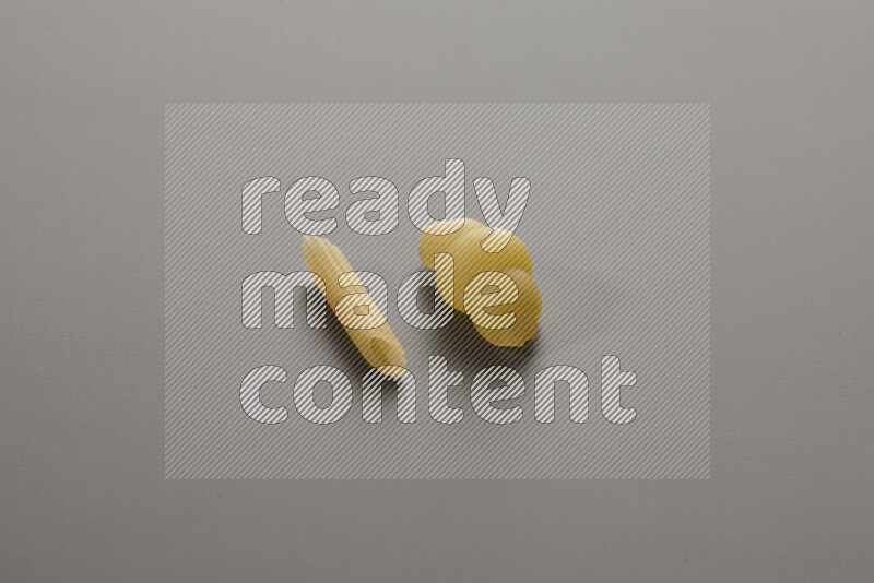 Mini penne pasta with other types of pasta on grey background