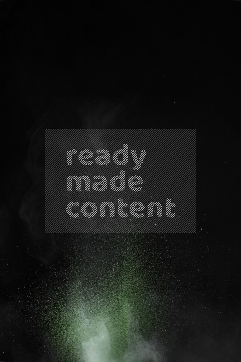 A side view of green powder explosion on black background