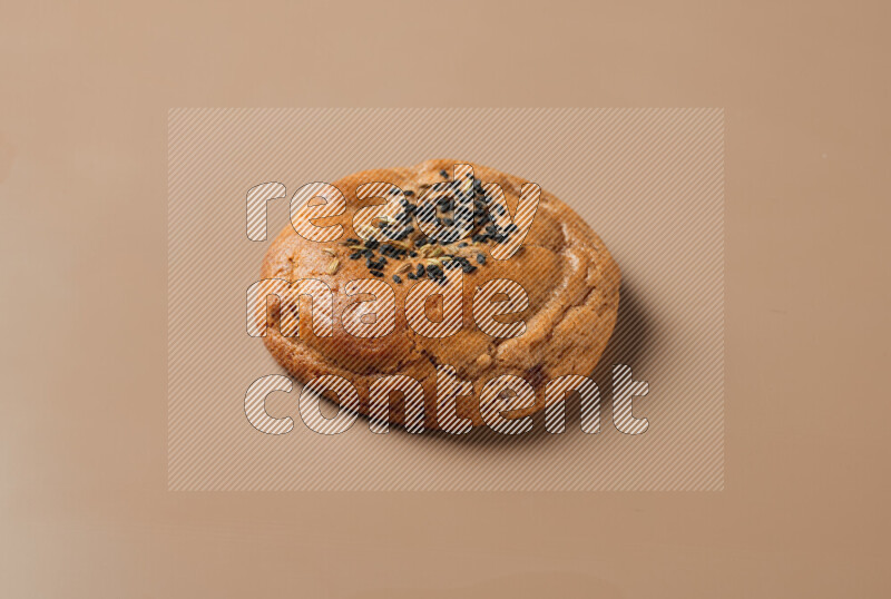 a whole Hasawi cookie with grains on a brown background