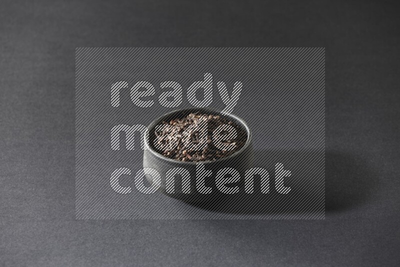 وعاء فخاري أسود ممتلئ بحبوب القرنفل علي خلفية سوداء