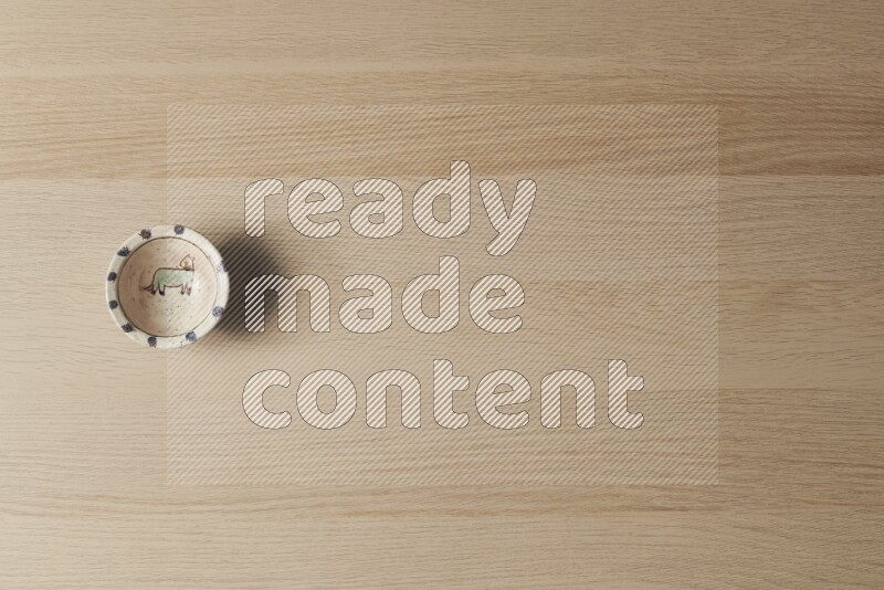 A decorative pottery bowl on light wooden background