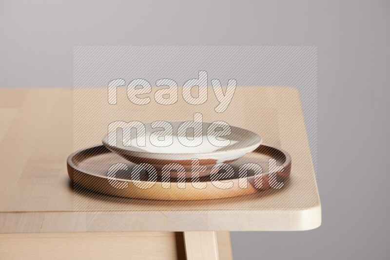 multi-colored pottery Plate placed on a light colored wooden tray on the edge of wooden table
