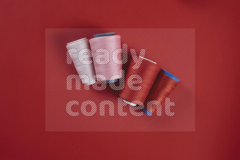 مجموعة من أدوات الخياطة والتفصيل زهرية وحمراء اللون على خلفية حمراء