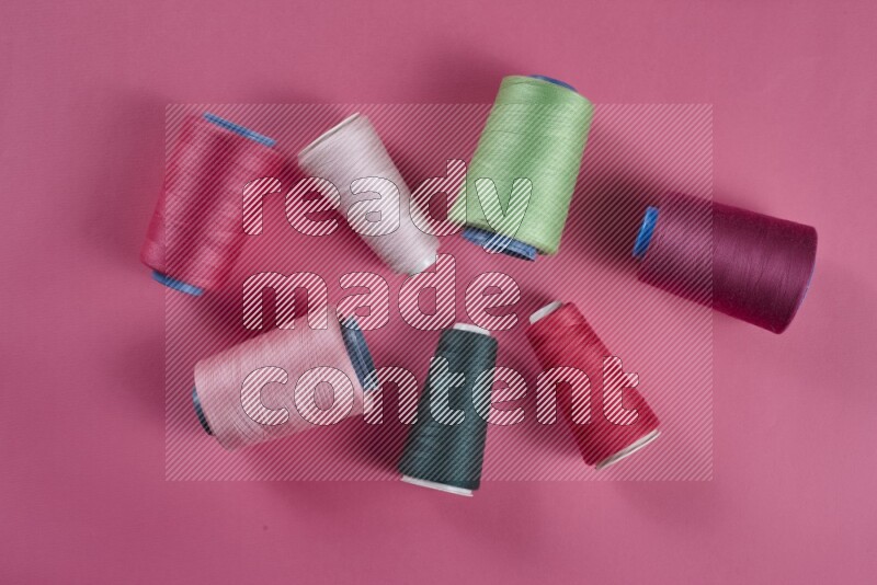 A green and pink collection of sewing and tailoring tools arranged on a pink background