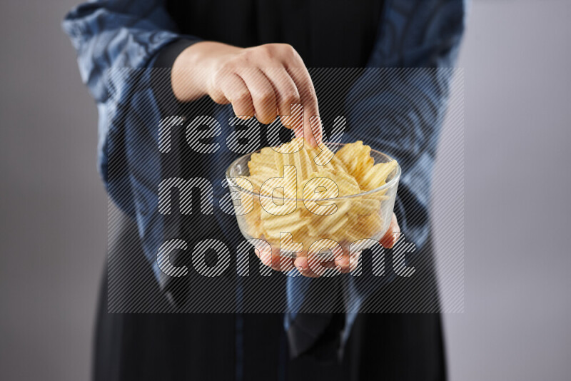 Woman in abaya holding different kinds of snacks in different positions