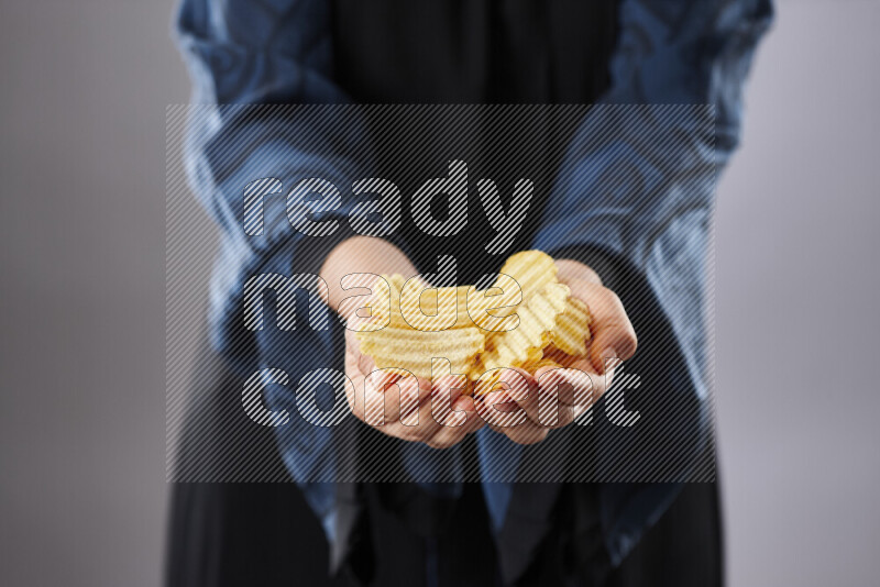 Woman in abaya holding different kinds of snacks in different positions