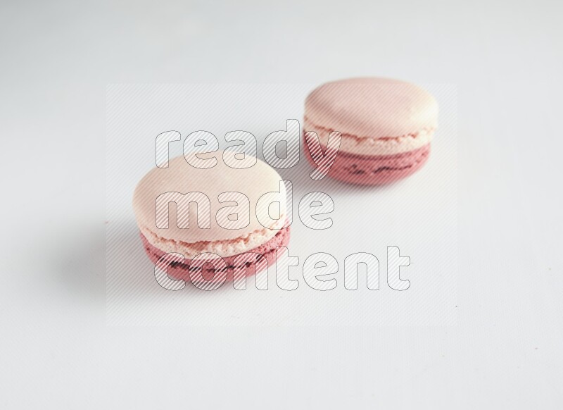 45º Shot of two Pink Litchi Raspberry macarons on white background