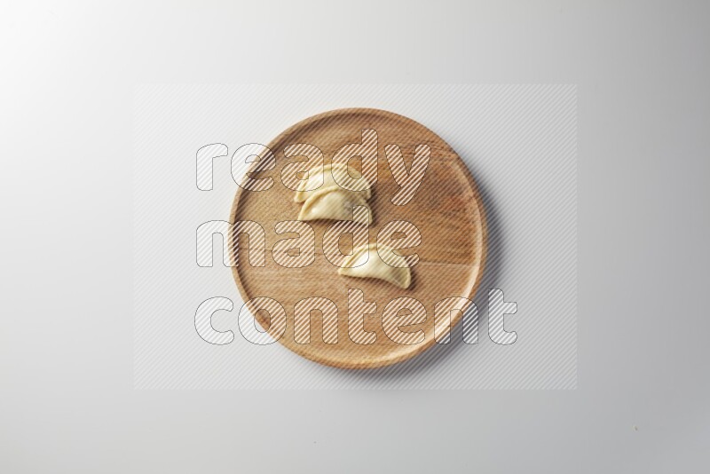 Three Sambosas on a wooden round plate on a white background