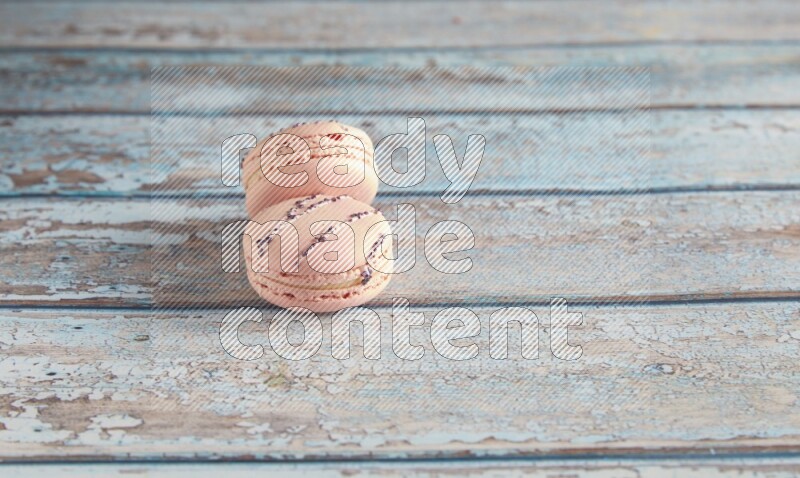 45º Shot of two pink orange blossom macarons on light blue wooden background