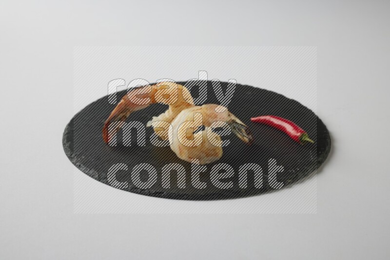 two grilled shrimp  on a black slate direct  on a white back ground