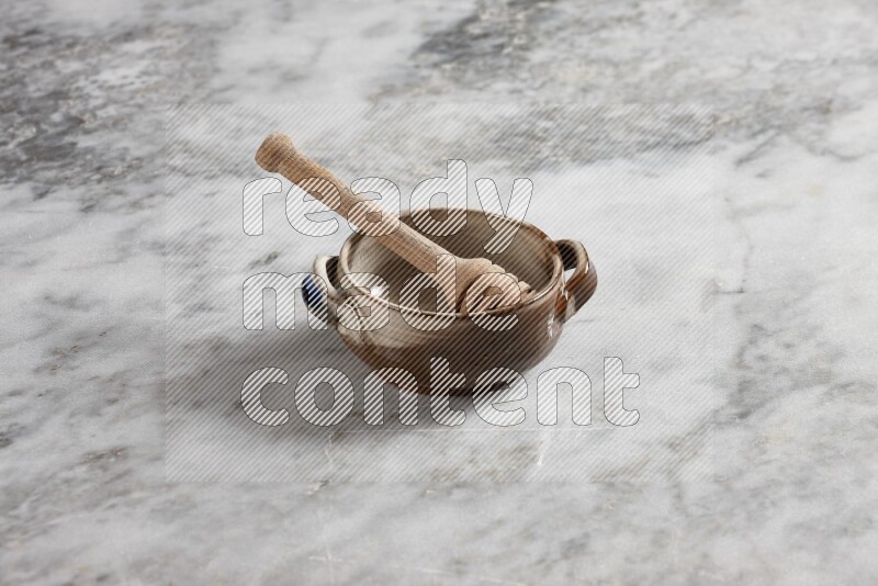Multicolored pottery bowl with wooden honey dipper in it on grey marble background