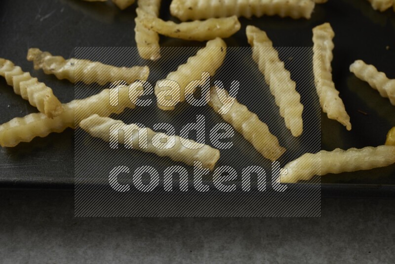 crinkle fries in a black stainless steel rectangle tray on grey textured counter top