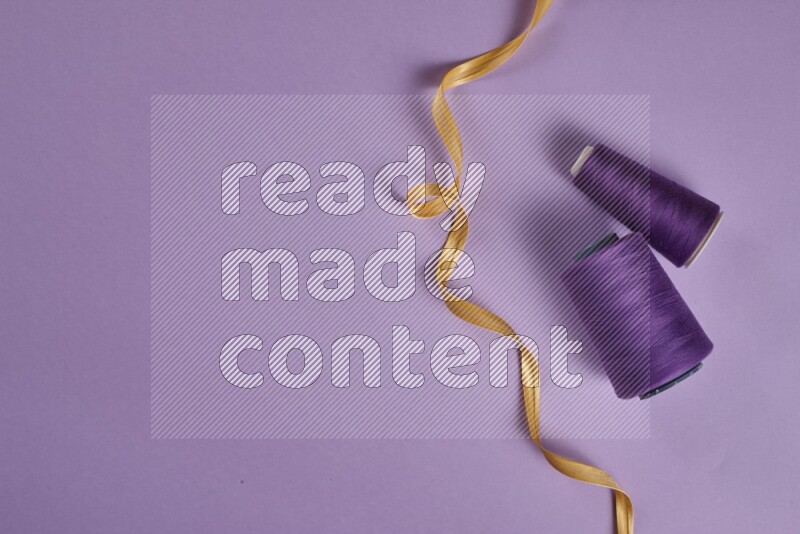 مجموعة من أدوات الخياطة والتفصيل صفراء وأرجوانية اللون على خلفية أرجوانية