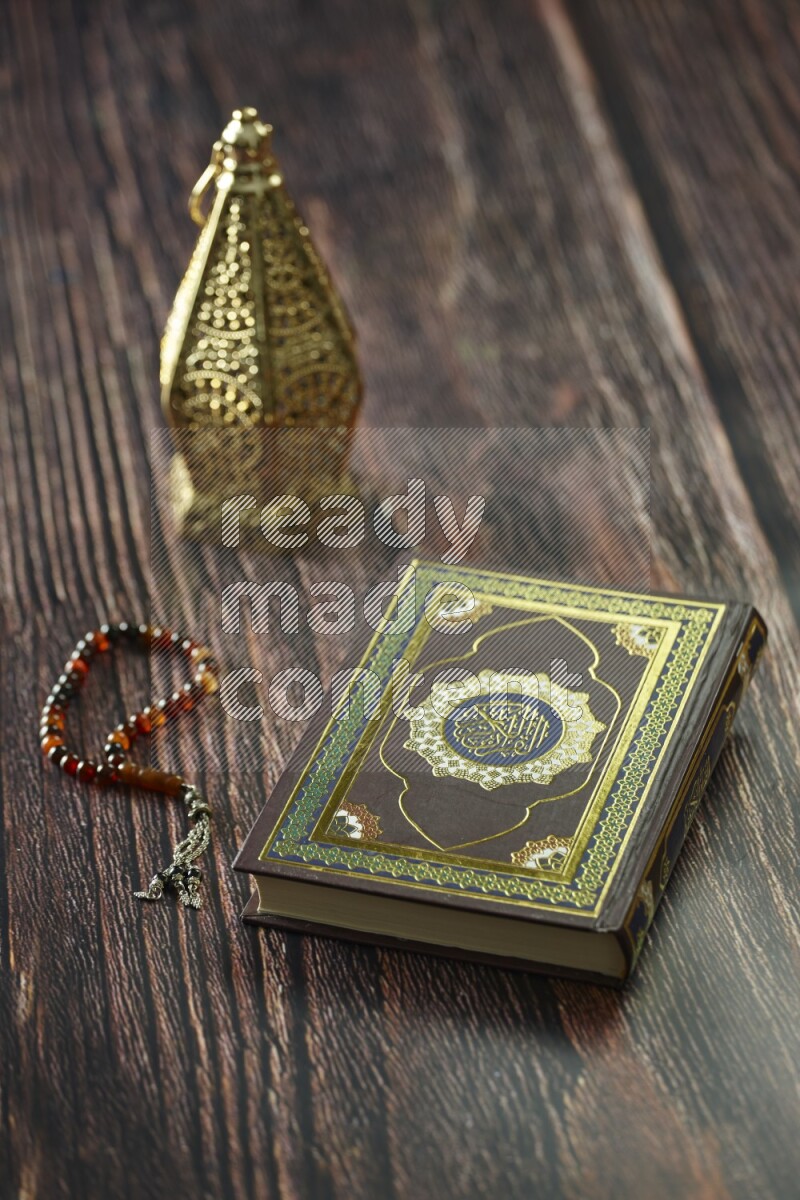 A golden lantern with different drinks, dates, nuts, prayer beads and quran on brown wooden background