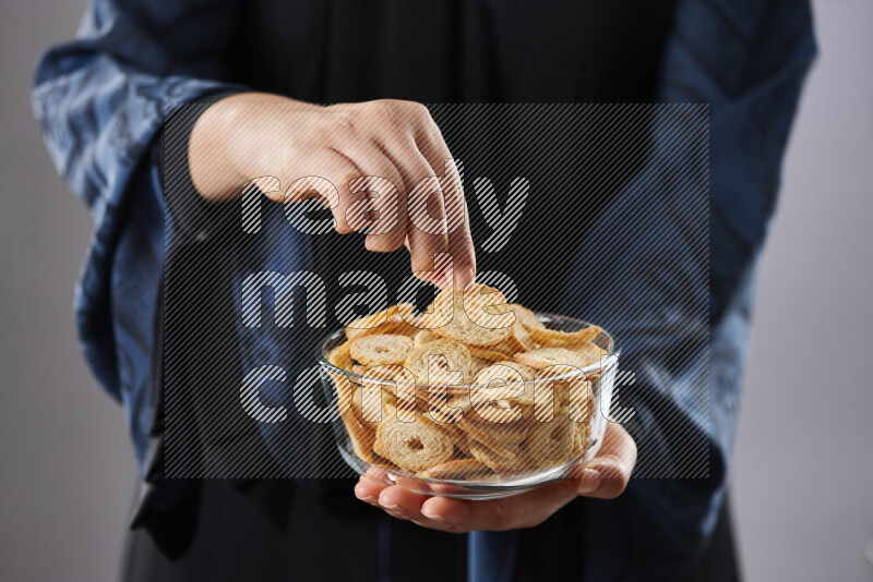 Woman in abaya holding different kinds of snacks in different positions
