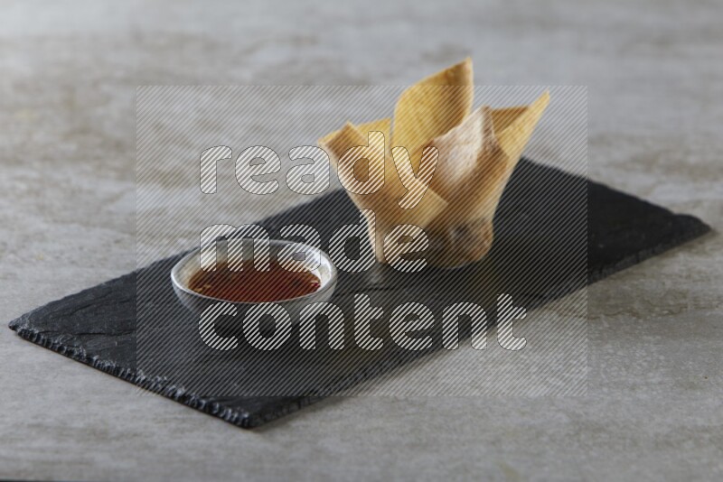 wonton cups with soy sauce ramkin on rectangle slate on grey textured counter top