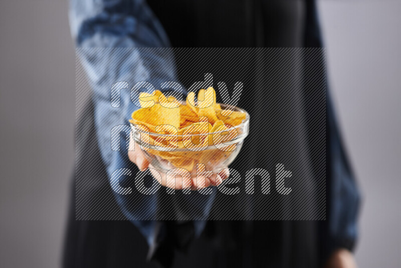 Woman in abaya holding different kinds of snacks in different positions