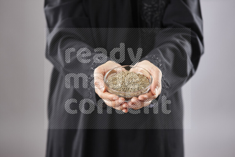Woman in abaya holding different kinds of spices in different positions
