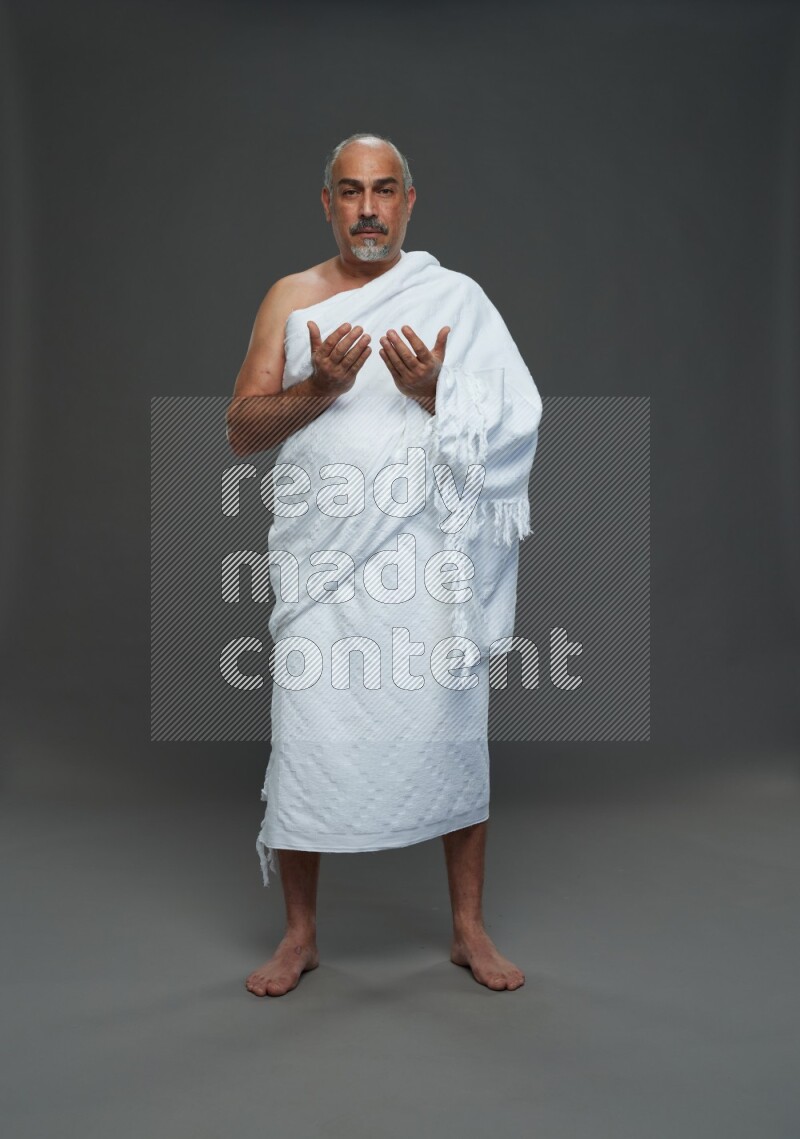 A man wearing Ehram Standing dua'a on gray background