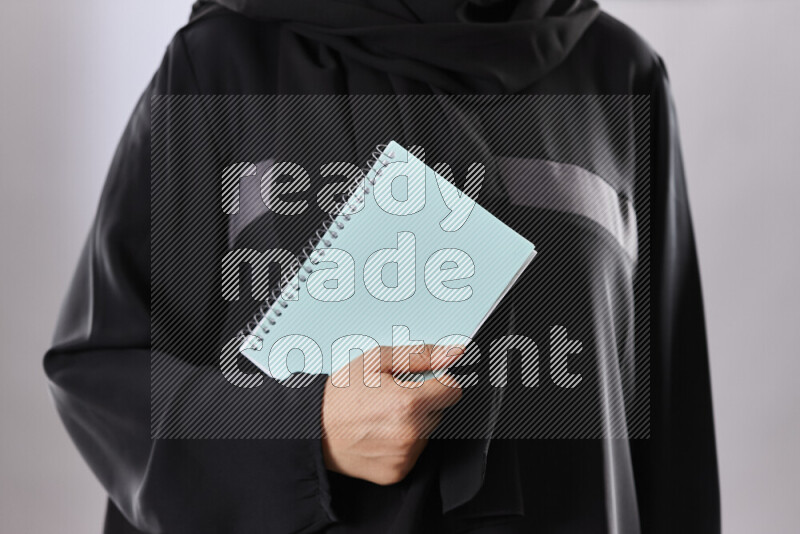 A woman in abaya holding books and a board in different positions (back to school)