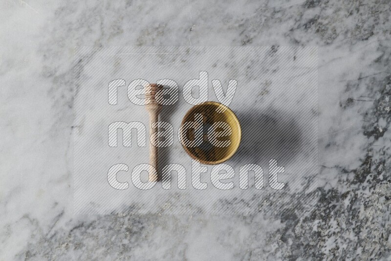 Multicolored pottery cup with wooden honey dipper on the side on grey marble background