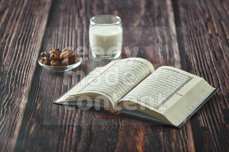 Quran with dates, prayer beads and different drinks all placed on wooden background