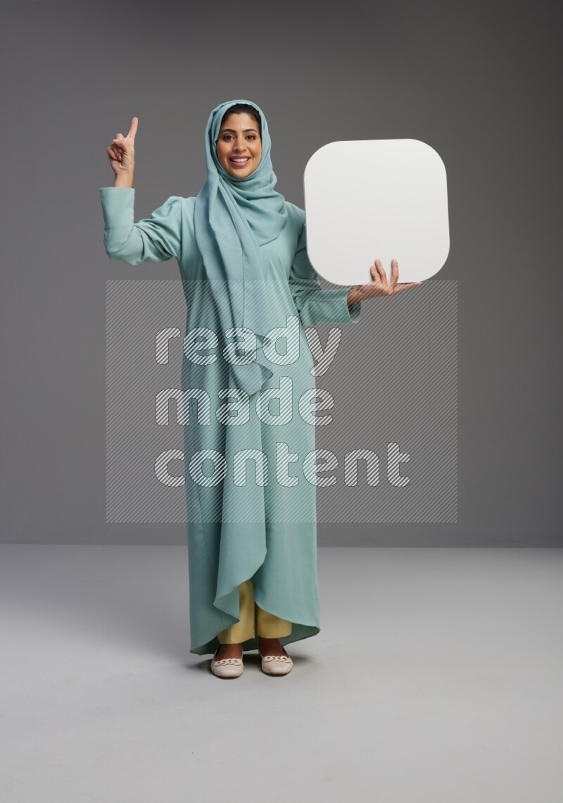 Saudi Woman wearing Abaya standing holding social media sign on Gray background