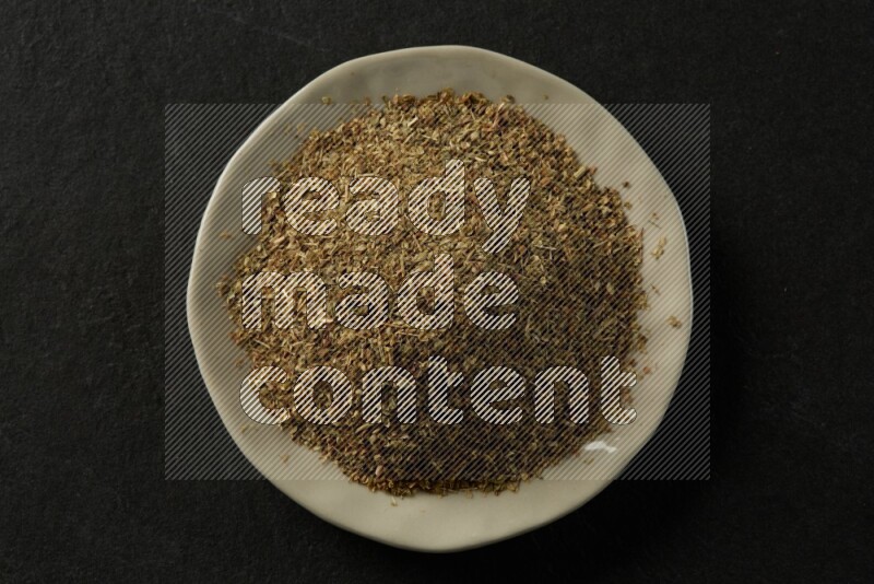 white ceramic round sauce dish filled with herbs on grey textured countertop