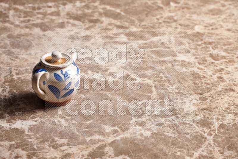 A pottery teapot on beige marble background