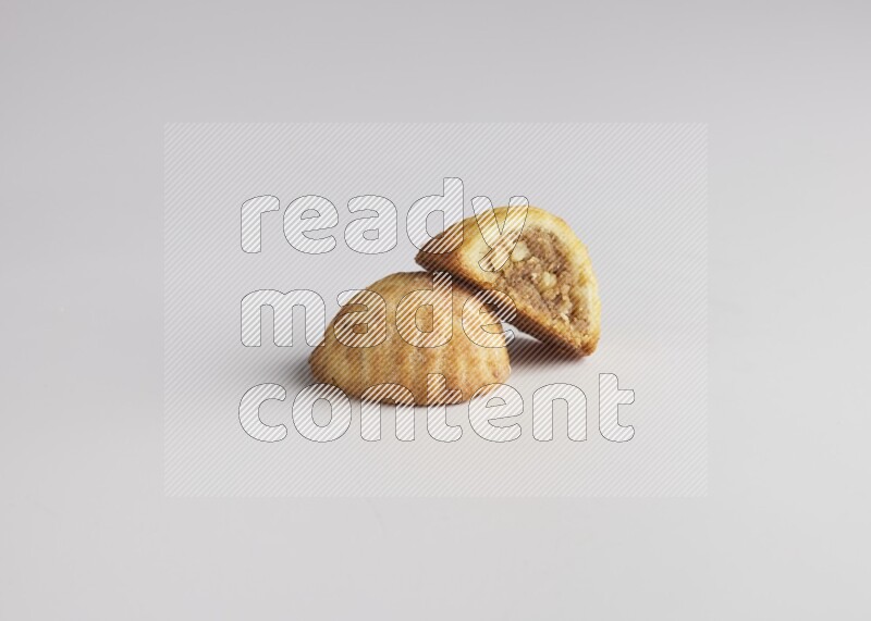 Two Pieces of Maamoul filled with walnut paste  one of them is cut direct on white background