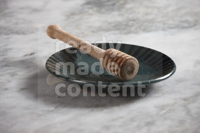 Multicolored pottery plate with wooden honey dipper in it on grey marble background