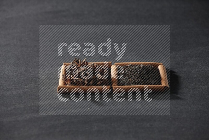 2 squares of cinnamon sticks full of star anise and black tea on black flooring