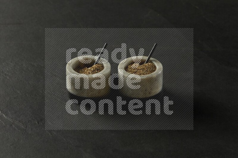 black and white round marble containers filled with herbs on gray textured countertop