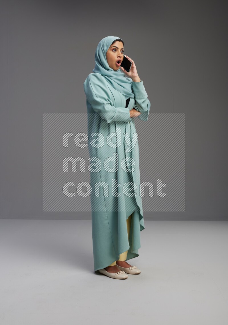 Saudi Woman wearing Abaya standing talking on phone on Gray background