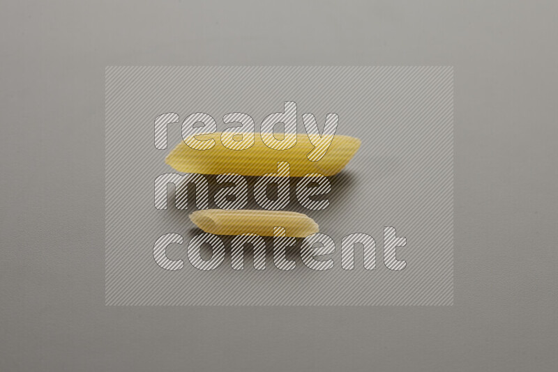 Penne pasta with other types of pasta on grey background