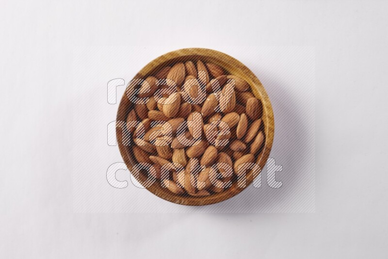 Almonds in a wooden bowl on white background