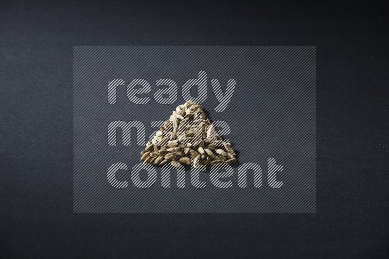 Cardamom in a triangle shape on black flooring