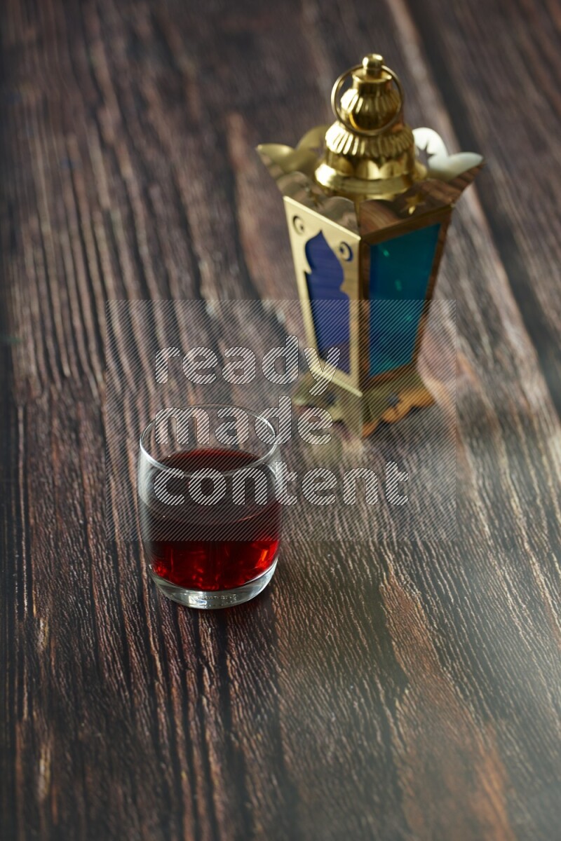 فانوس ذهبي مع مشروبات مختلفة وتمر ومكسرات وسبحة صلاة وقرآن على خلفية خشبية بنية