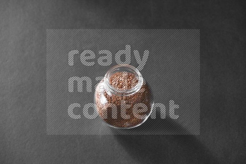 A glass spice jar full of flax on black flooring